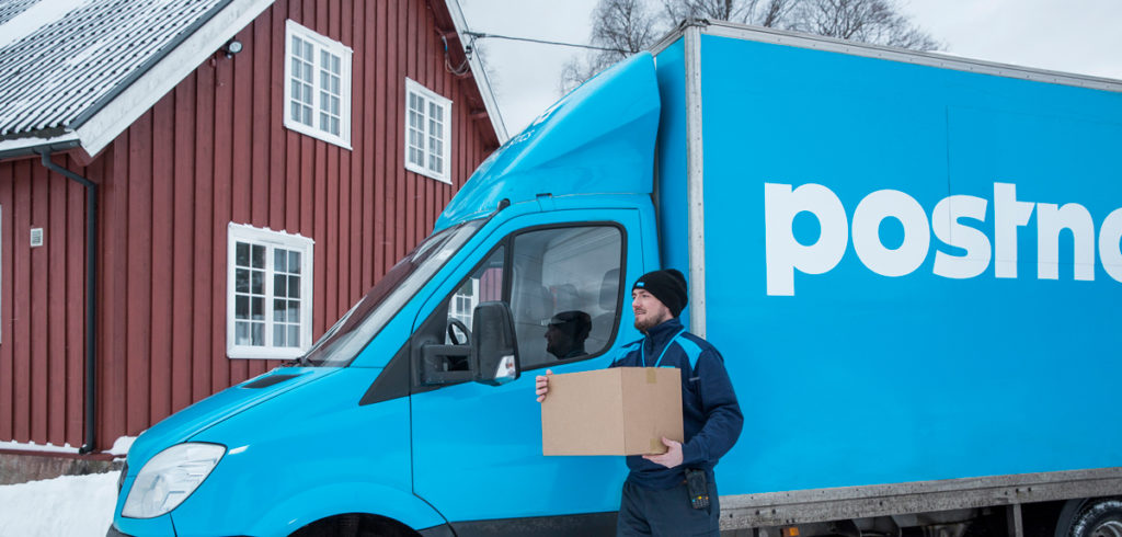Delivery man with parcel in front of blue PostNord van