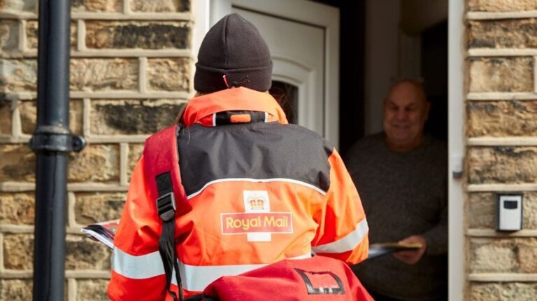 Royal Mail postal worker wearing an orange and black high vis uniform jacket delivering mail to home.