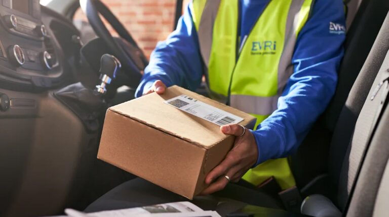 An Evri employee handles a parcel in the front cabin of a delivery vehicle, while wearing a yellow high-vis vest