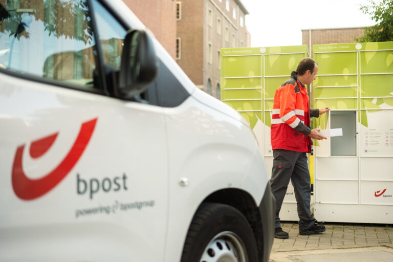bpost delivery person placing a parcel in a green parcel locker