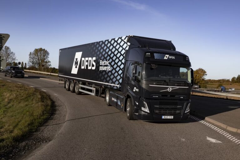 Volvo electric truck with DFDS logo on the side, traveling down the motorway