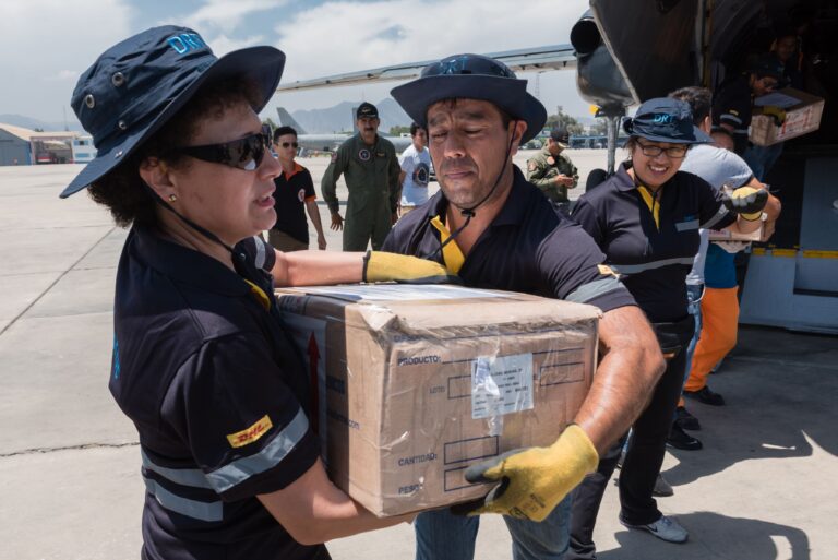 DHL employees taking aid boxes from a cargo plane