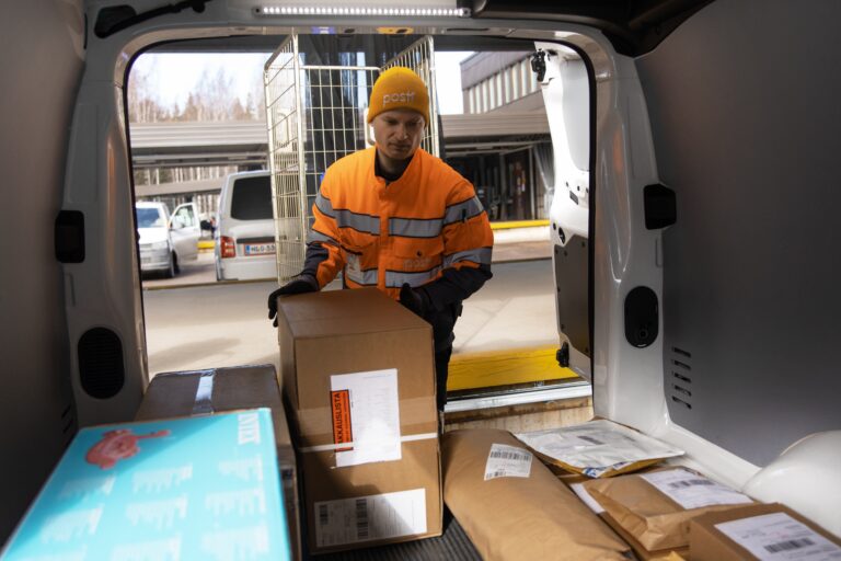 Posti worker placing parcels in a van for delivery