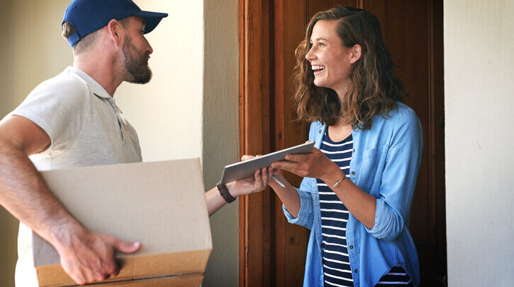 Happy woman, delivery man and box with tablet at door for order, parcel or cargo in transport service. Female person receiving shipment from male courier, supply chain or ecommerce purchase at home