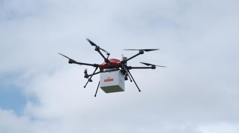 Drone in sky carrying Royal Mail parcel
