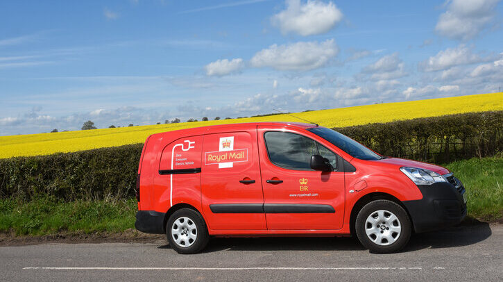 Royal Mail electric van driving along country road with blue sky and yellow corn field in background
