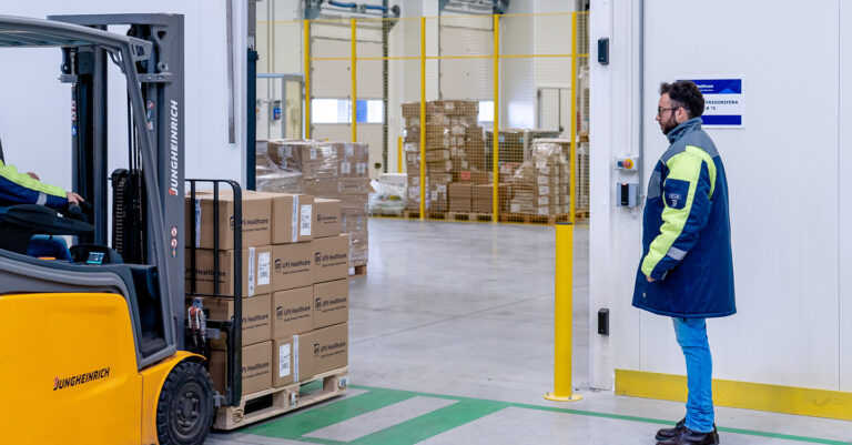 Forklift with UPS Healthcare packages on, worker standing nearby