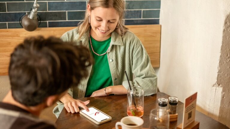 Woman looking at bpost app on her mobile phone while at cafe with man