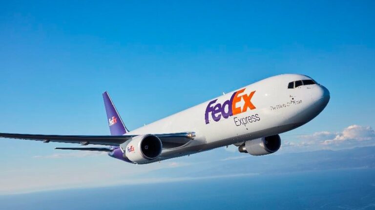 FedEx aircraft flying in blue sky.