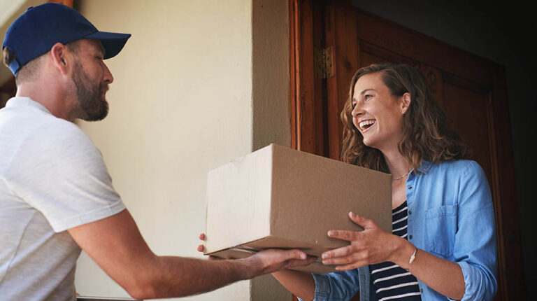 Happy woman, delivery man and package box at door for order, parcel or cargo of customer in transport service. Female person receiving shipment from male courier, supply chain or deliver at the house