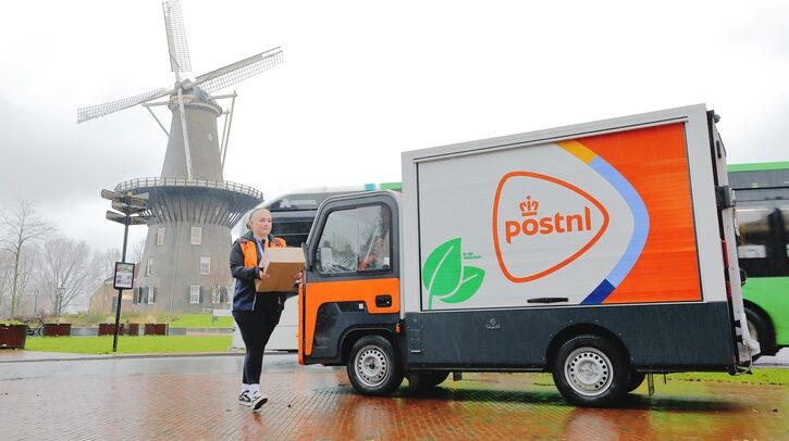A PostNL delivery truck parked in front of a windmill