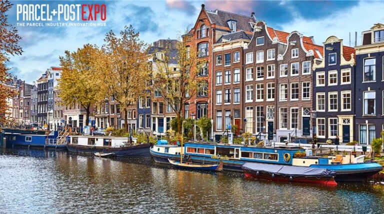 A photo of a canal in Amsterdam with a bright blue sky and boats moored along the edge of the water