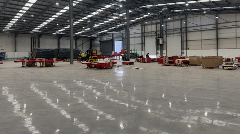 The inside of the new DHl eCommerce facility in Birmingham, UK, with an mostly-empty floorspace and sorting equipment being installed