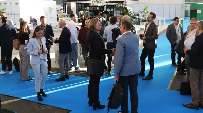 Parcel+Post Expo attendees talk at a networking event, with a coffee cart pop-up behind them