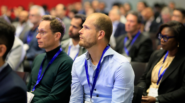 Attendees sit in rows at the conference at Parcel+Post Expo listening to a presentation