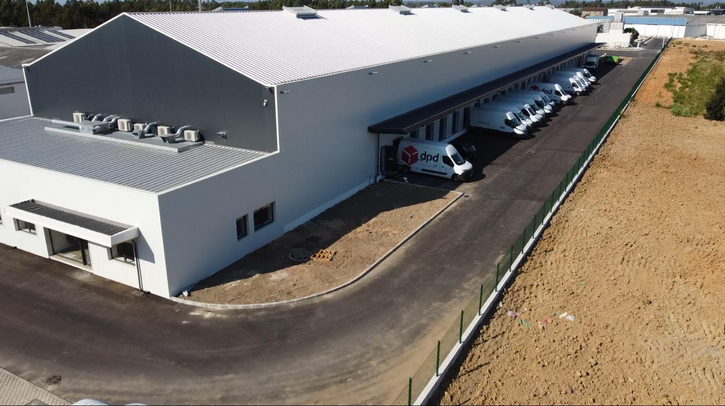 An exterior shot of the new Leira depot in Portugal, with DPD vans and trucks out the front and a blue sky above