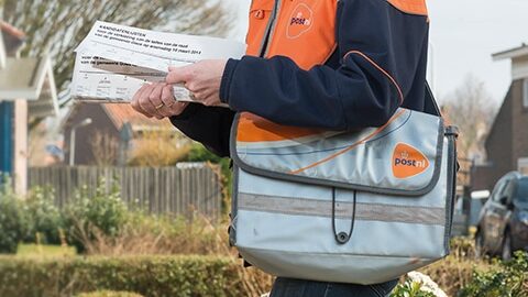 PostNL delivery worker with branded satchel and mail in hand