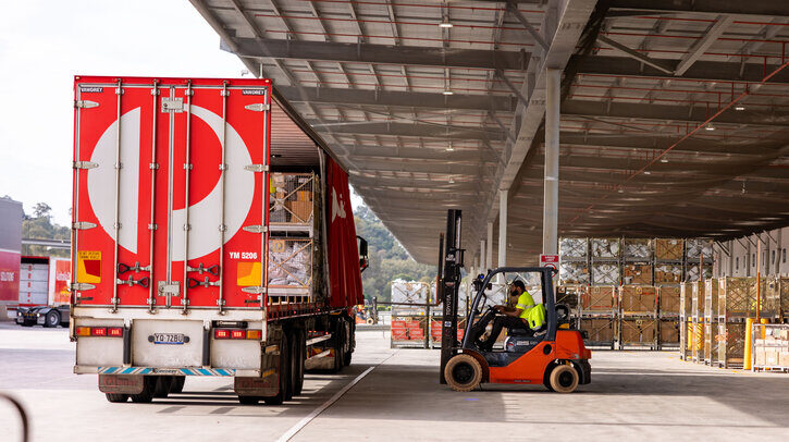 An Australia Post delviery truck parked at a sorting facility with a forklift loading cargo