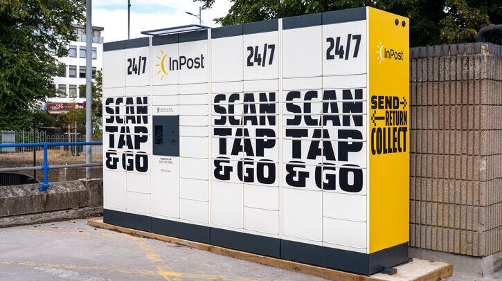 A bank of inPost lockers on a street against a brick wall