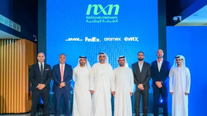 Members of 7Z stand in front of a blue board of company logos at the launch of the NXN national logistics network