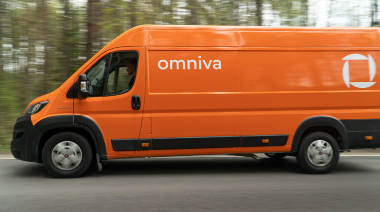An orange delivery van with Omniva written along the side drives down a tree-lined road