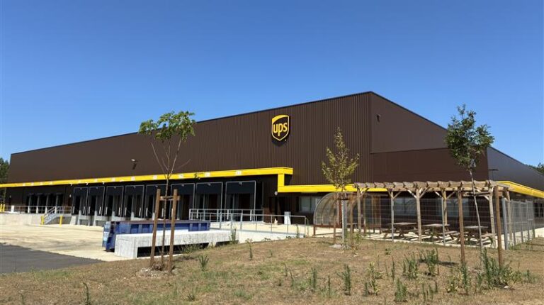 UPS’s new 7,200m2 parcel hub in Dax, France, with grass an small, young trees out the front and a blue sky above