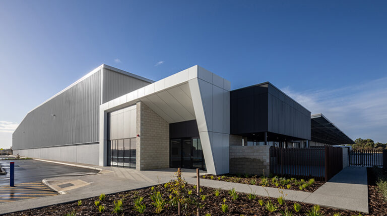 The new Australia Post parcel facility in Perth, with a frontage comprising contrasting angles and beams, with a white section and a black section. The sky is blue.