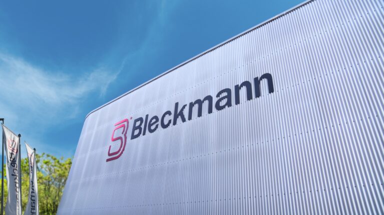 A grey warehouse logistics facility with the name Bleckmann in blue writing on the outside.