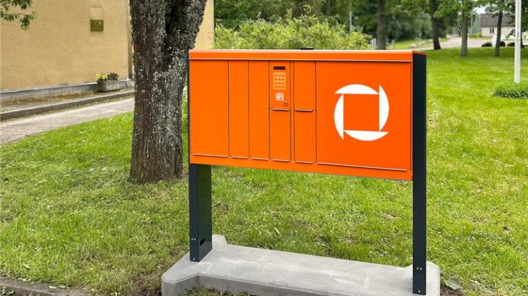 An orange Omniva locker at the edge of a park.