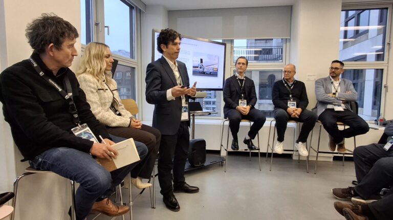 Carlos Setien, innovation manager at International Post Corporation, discusses postal regulation in a workshop in a small room in front of a projector screen.