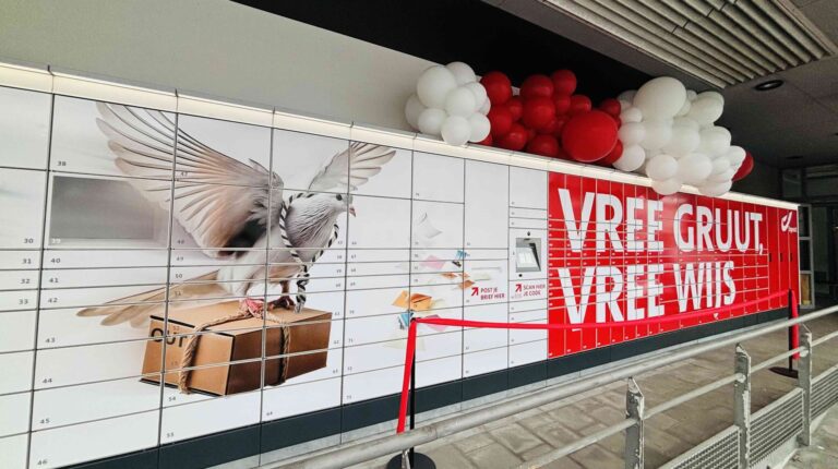 The Bpost parcel locker facility in Ghent in Belgium, with banks of lockers. It is white with some red advertising on one end.